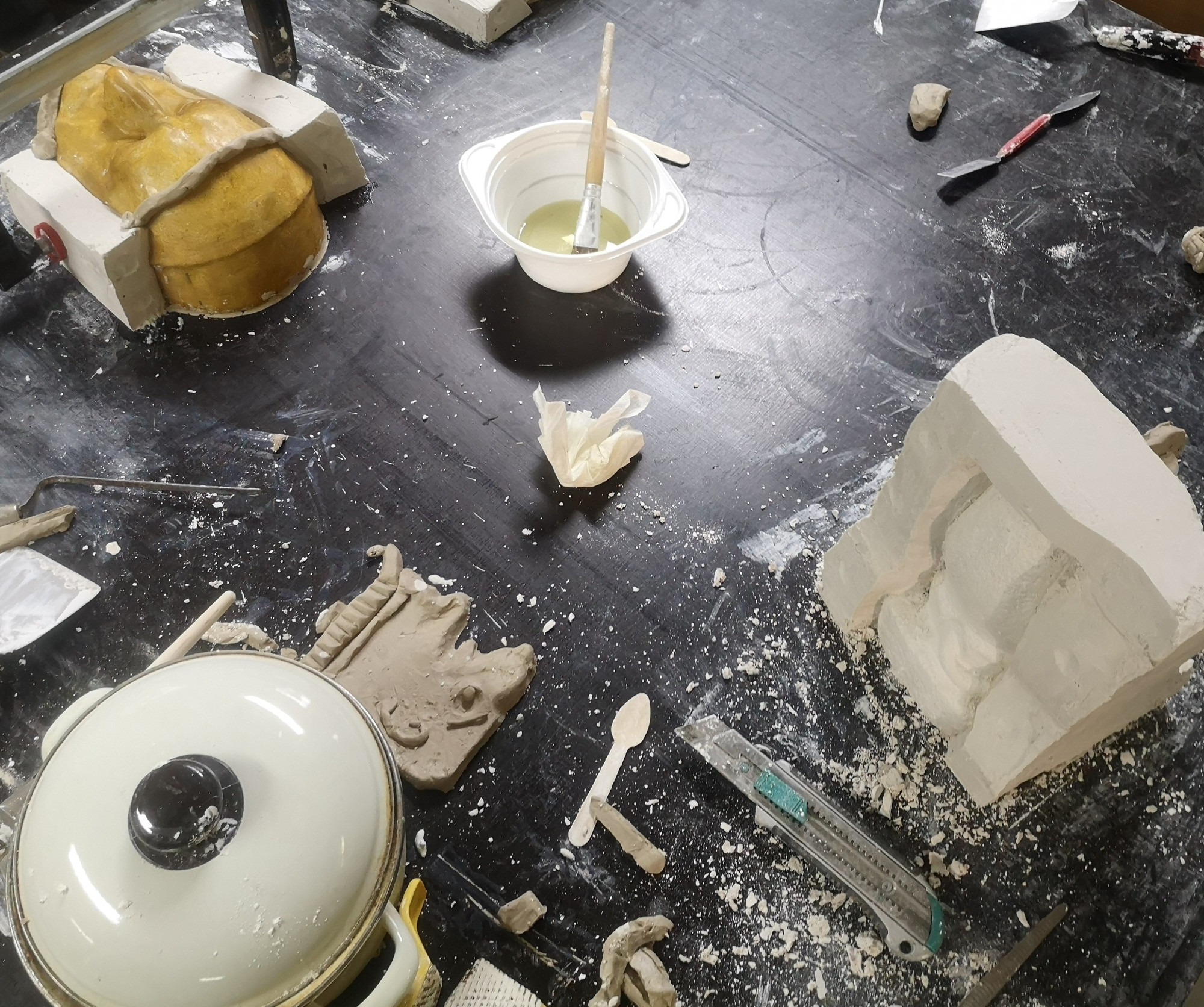 Arbeitstisch mit Topf, Pinsel im Becher und Abformmodellen.
