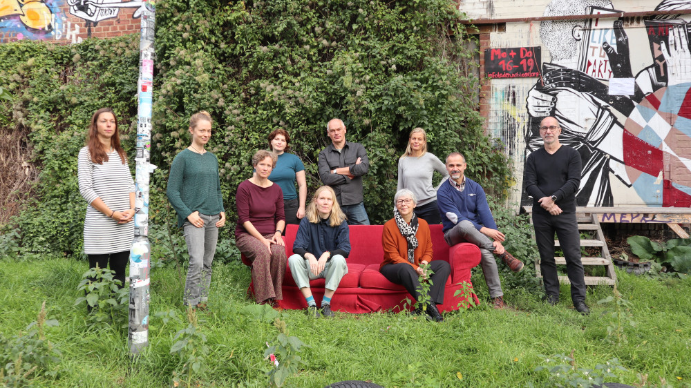 Das Projektteam der Leipziger Denkmalstiftung sitzt auf und steht neben einem Sofa auf einer grünen Wiese.