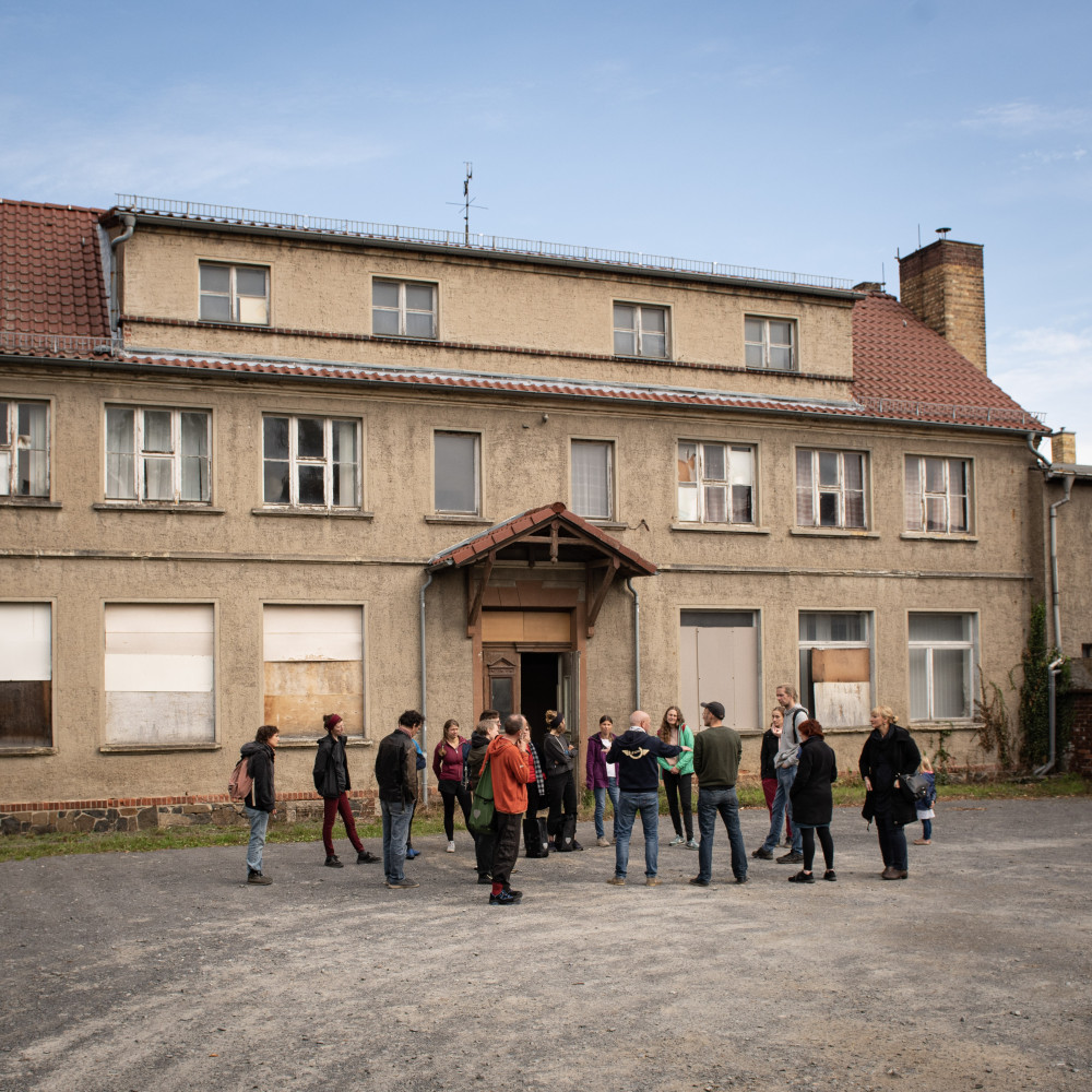 mehrere Menschen stehen vor einem unsanierten Haus